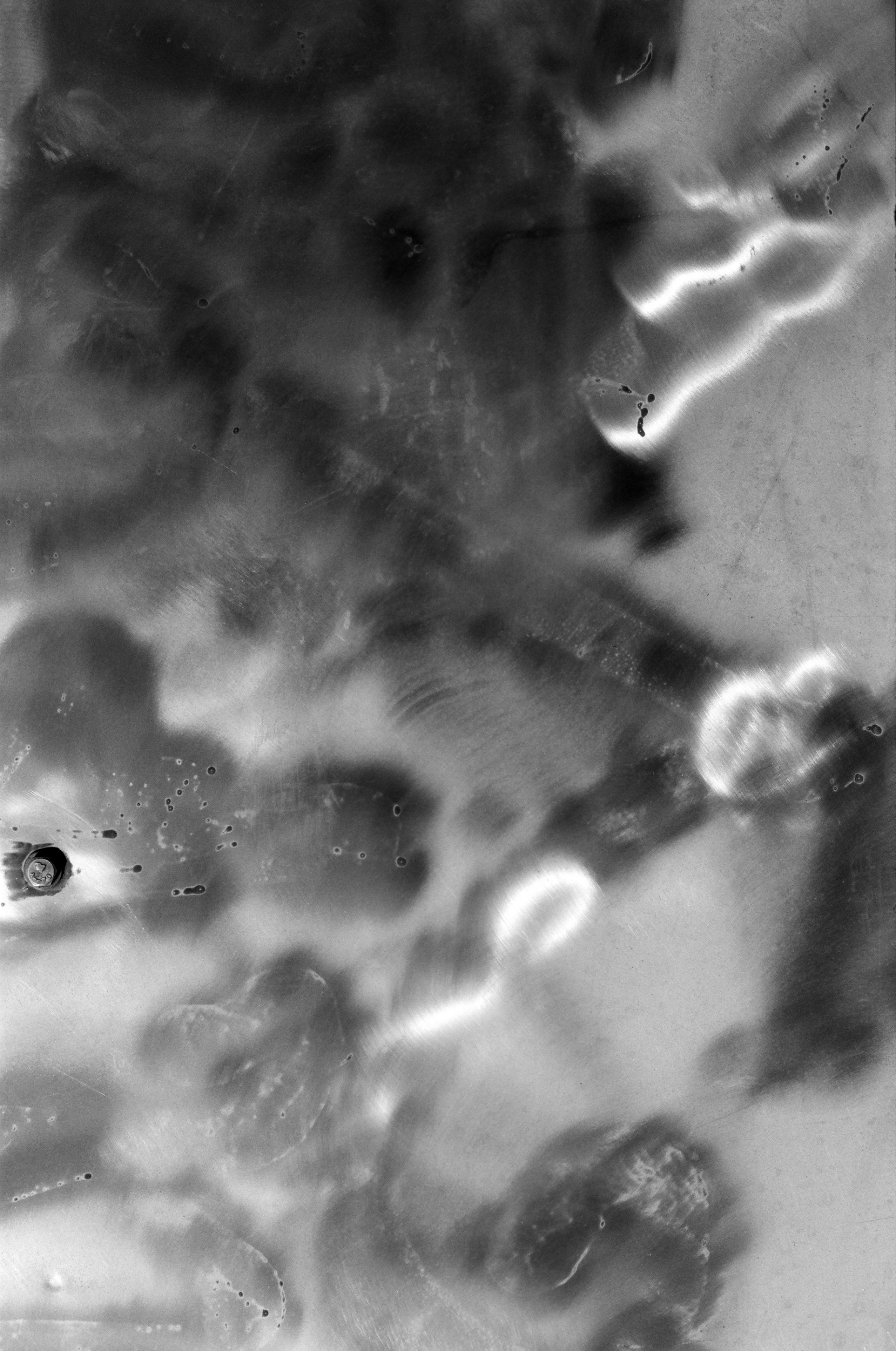 Abstract monochromatic surface with glowing light streaks, dark smudges, and visible scratches.