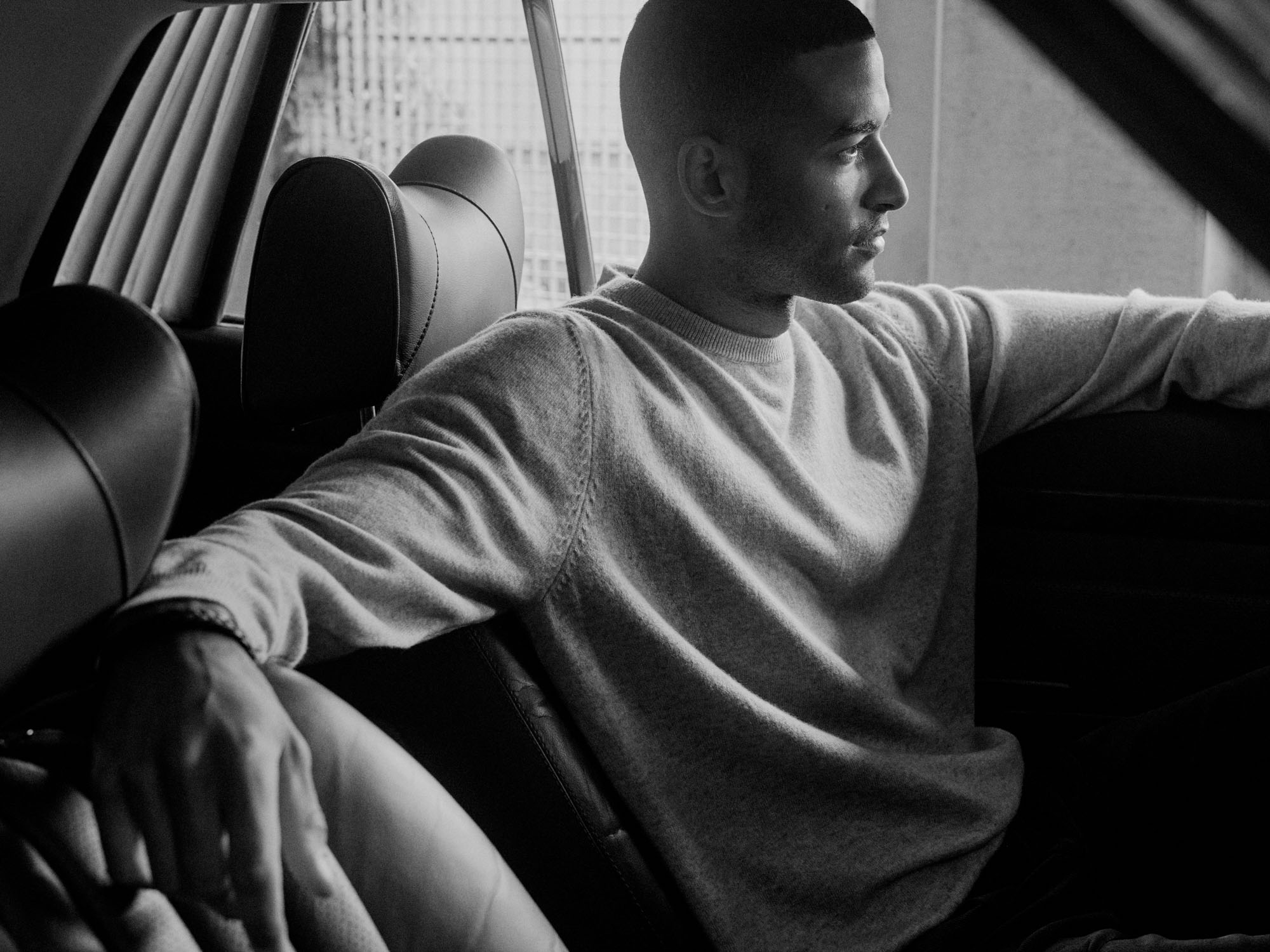 Black and white profile of a man in a light sweater sitting in a car